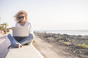 Frau arbeitet mit Laptop am Strand